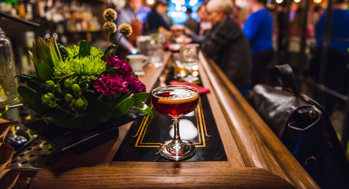 Independence square in Kyivlong bar counter with cocktail and flowers and people on the background