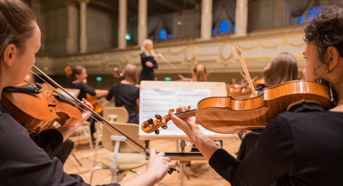 musicians playing violins in orchestra