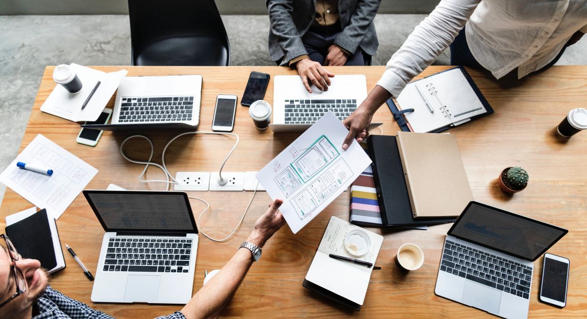 people around table with laptops and documents