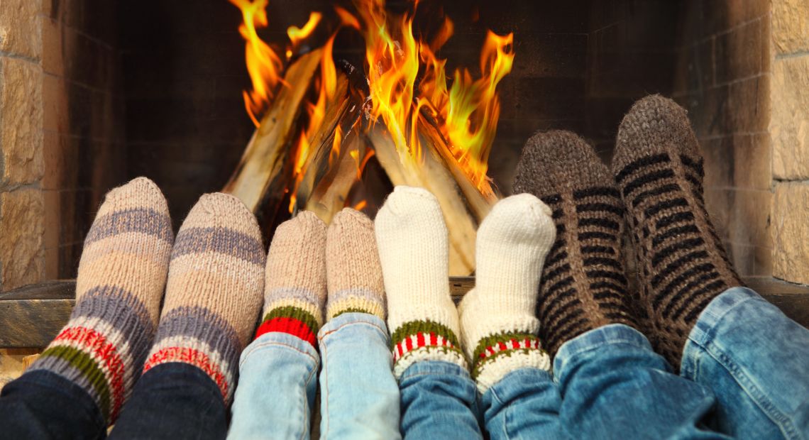 four pairs of legs in socks in front of fireplace