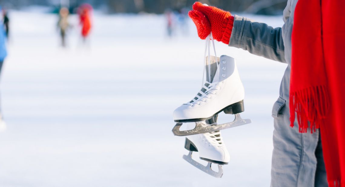 Person in red mittens holding ice skates