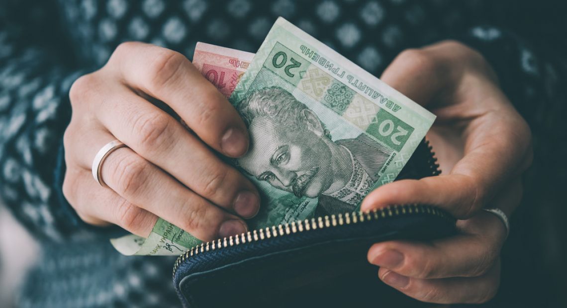 Person holding a purse with 20 Hryvnia banknote