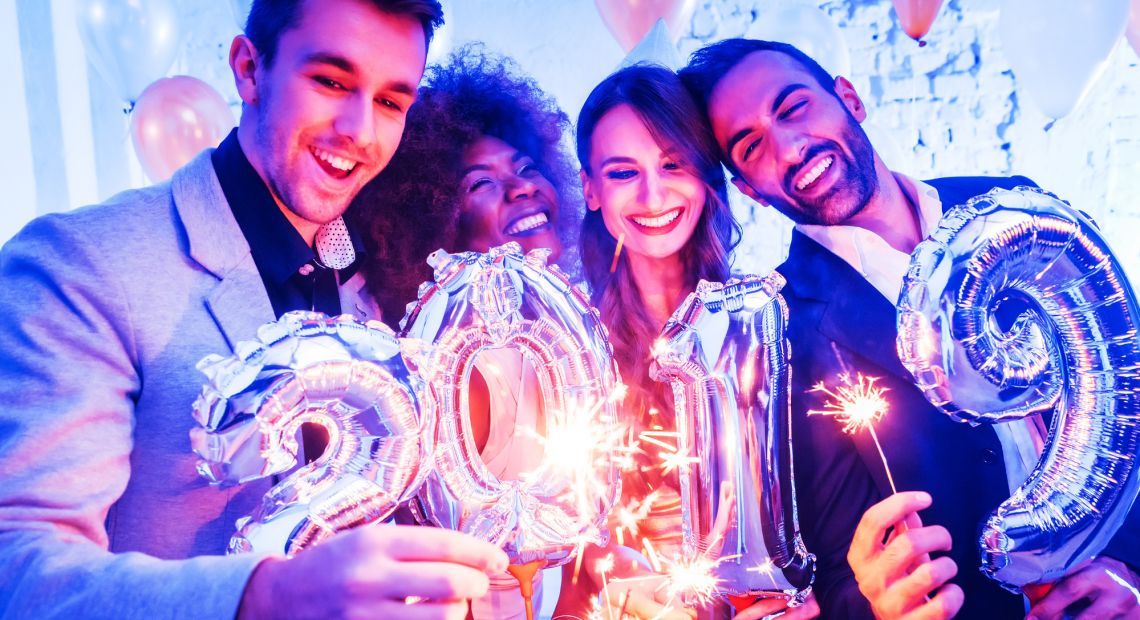 four friends at party holding bengal lights and air balloons