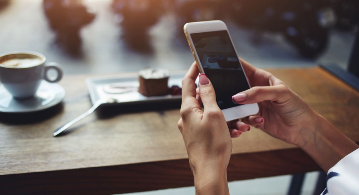 female hands holding smartphone in coffee shop