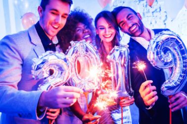four friends at party holding bengal lights and air balloons
