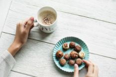 Person picking sweets and holding a cup of coffee