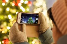 Person holding a phone and taking a pic of a Christmas tree