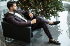 Man in a suit sitting by the Christmas tree