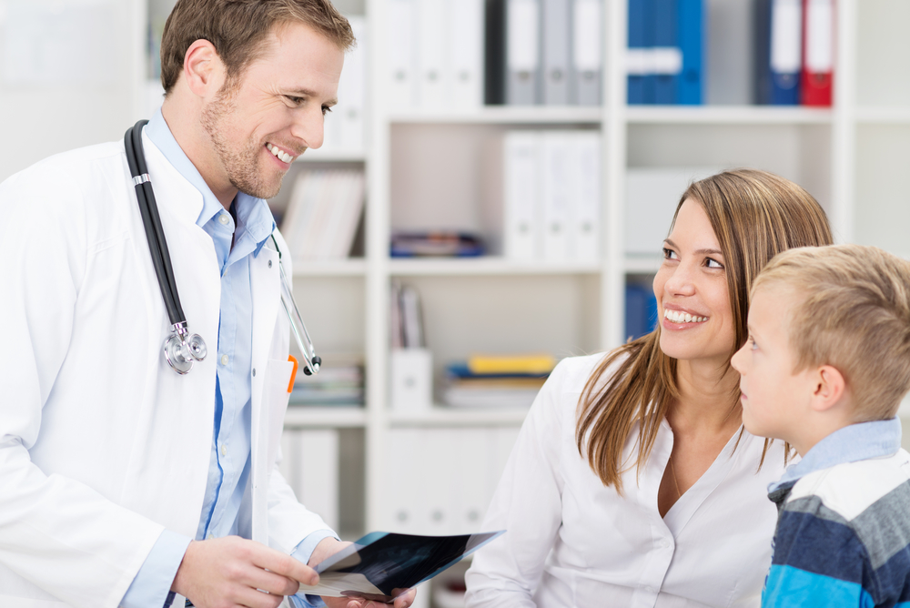 male and female doctors laughing and smiling with kid
