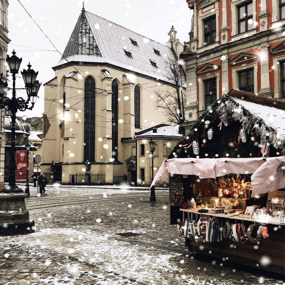 street with old buildings, lanterns, people and christmas fair spot in winter