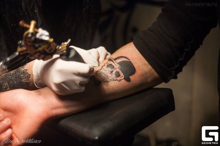hands of tattoo master and client, getting a skull tattoo