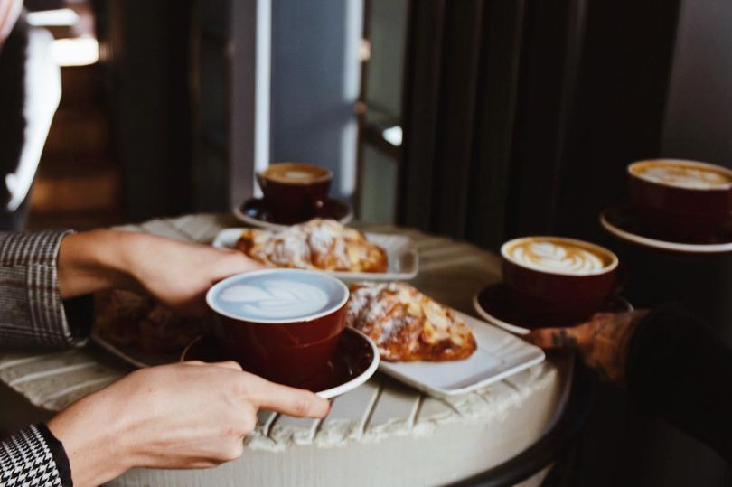 hands on table with bread and coffee