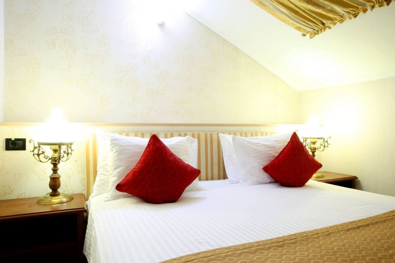 bed in hotel room with white sheets and red pillows