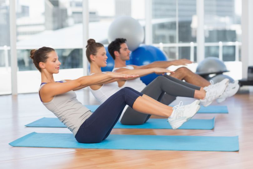 men and women exercising on yoga mats in gym